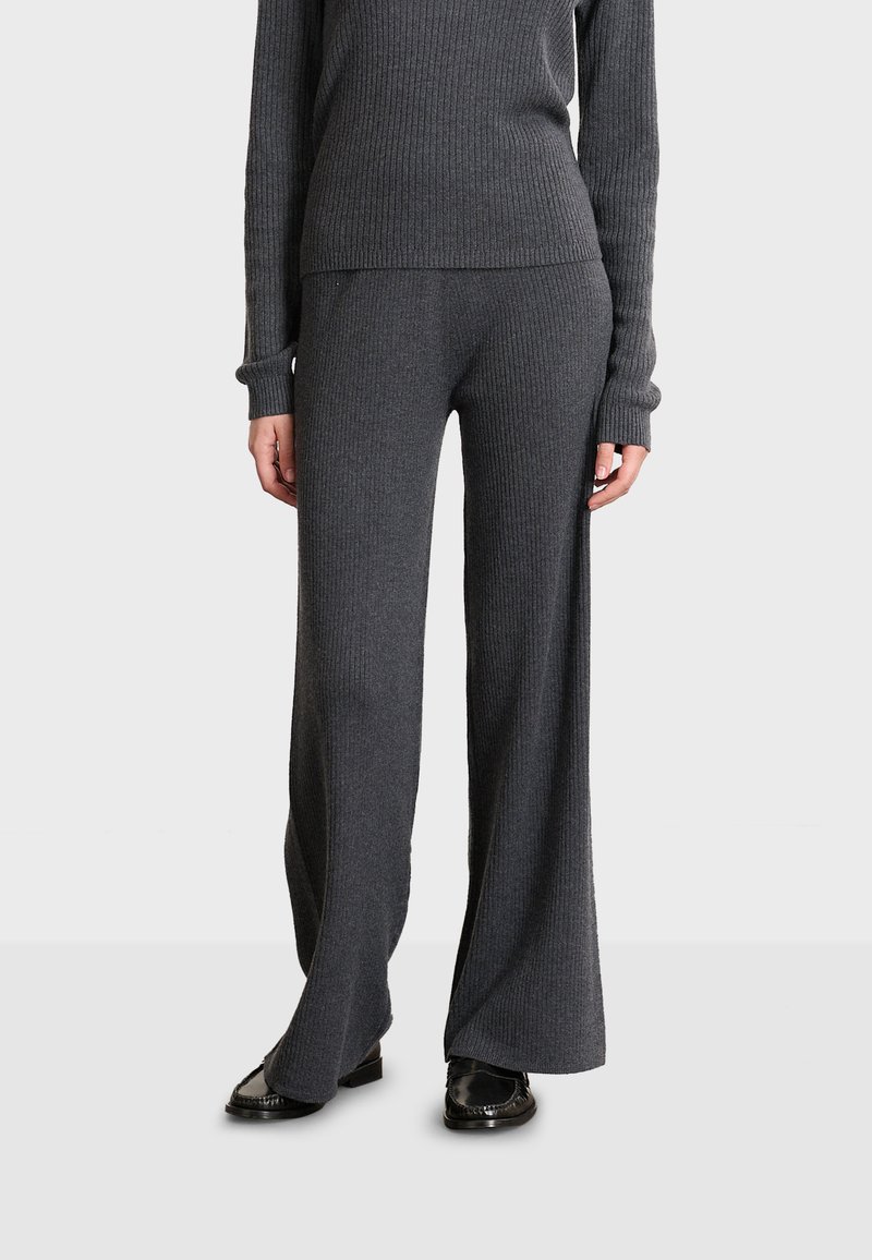 Jersey de punto gris con canalé y pantalones de pierna ancha, que presentan mangas largas, una silueta ajustada y una textura suave, combinados con zapatos negros.