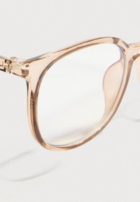 Διαφανή, ανοιχτό ροζ πλαστικά γυαλιά με παχιά πλαίσια, ελαφρώς στρογγυλεμένες άκρες και διαυγή φακούς που αντανακλούν το φως, με μεταλλικό μεντεσέ.