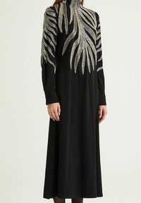 Abito nero a maniche lunghe con collo alto, caratterizzato da motivi di foglie argentate metalliche lungo le maniche, realizzato in tessuto liscio e fluente.