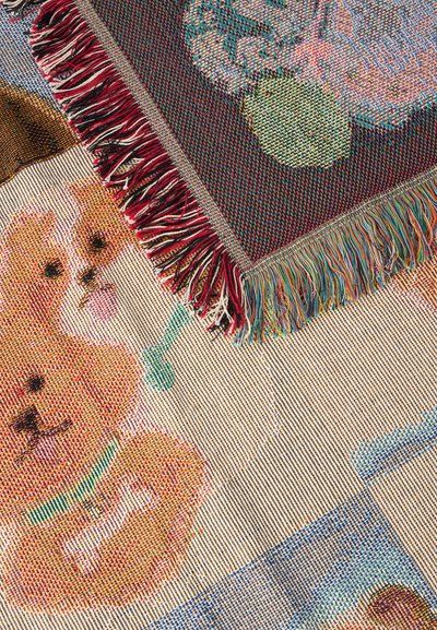 Des couvertures tissées aux bords frangés montrent des visages de chiens et des motifs colorés en gros plan, mettant en valeur les textures textiles et les dessins détaillés.