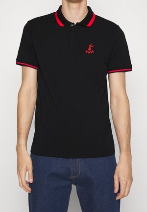 Sort poloshirt med rød krave og ærmekanter, med et diskret broderet logo på brystet. Fremstillet af glat, åndbart stof.