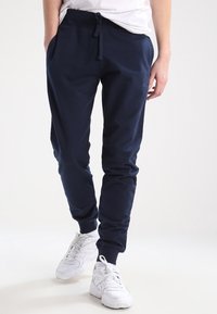 Pantalones deportivos azul marino con cintura con cordón, bolsillos laterales y tobillos con puños, hechos de tela suave y texturizada para mayor comodidad y ajuste.