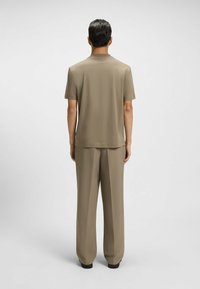 Camicia a maniche corte color crema e pantaloni larghi coordinati, entrambi realizzati in tessuto morbido, progettati per una vestibilità relax, con dettagli minimi.