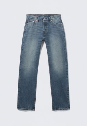 Plave traperice ravnog kroja, srednje pranje s izblijedjelim dijelovima, pet džepova, bakreni zakovice i kontrastni detalji šavova.