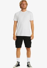Hvid bomulds-t-shirt, sorte cargo-shorts og højtoppede sneakers. Shortsene har sidelommer; en klassisk pasform med korte ærmer.