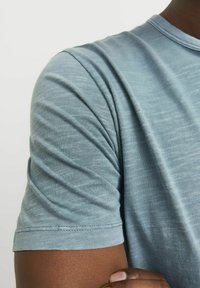 Lyseblå kortærmet t-shirt lavet af blødt stof, med rund halsudskæring og ribbet detaljering på ærmeenderne.