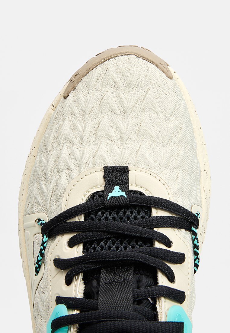 Baskets de sport beige clair avec surface texturée, lacets noirs et accents turquoise. Présentent une languette rembourrée et une semelle en caoutchouc durable.