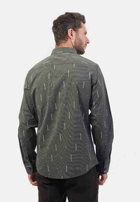 Camicia a maniche lunghe di colore verde scuro con strisce bianche verticali e motivi a pois sparsi. Polsini con bottoni e colletto classico.