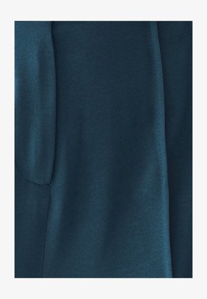 Głęboki szmaragdowy materiał o gładkiej teksturze, z diagonalnym wzorem splotu. Krawędzie są starannie wykończone, co podkreśla prostotę wzoru.