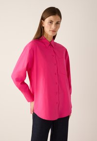 Langärmliges Hemd in leuchtendem Pink aus glattem Stoff, mit Kragen, Knopfleiste und linker Brusttasche, mit entspanntem Schnitt.