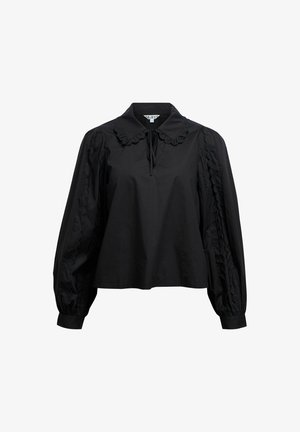 Svart langermet skjorte med krage, med volanger og teksturerte paneldetaljer langs ermene. Mykt bomullsmateriale.