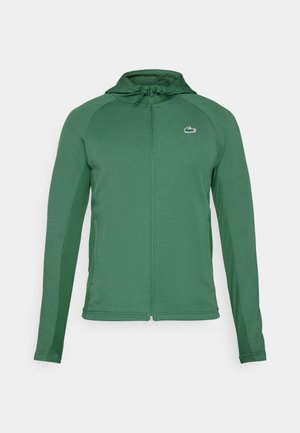 Felpa verde con zip realizzata in tessuto testurizzato, dal design aderente, dotata di cappuccio, tasche e un piccolo logo sul petto.