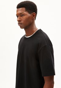 Black cotton t-shirt with a round neckline, short sleeves, and a relaxed fit, featuring minimal seams and no visible patterns or accents.