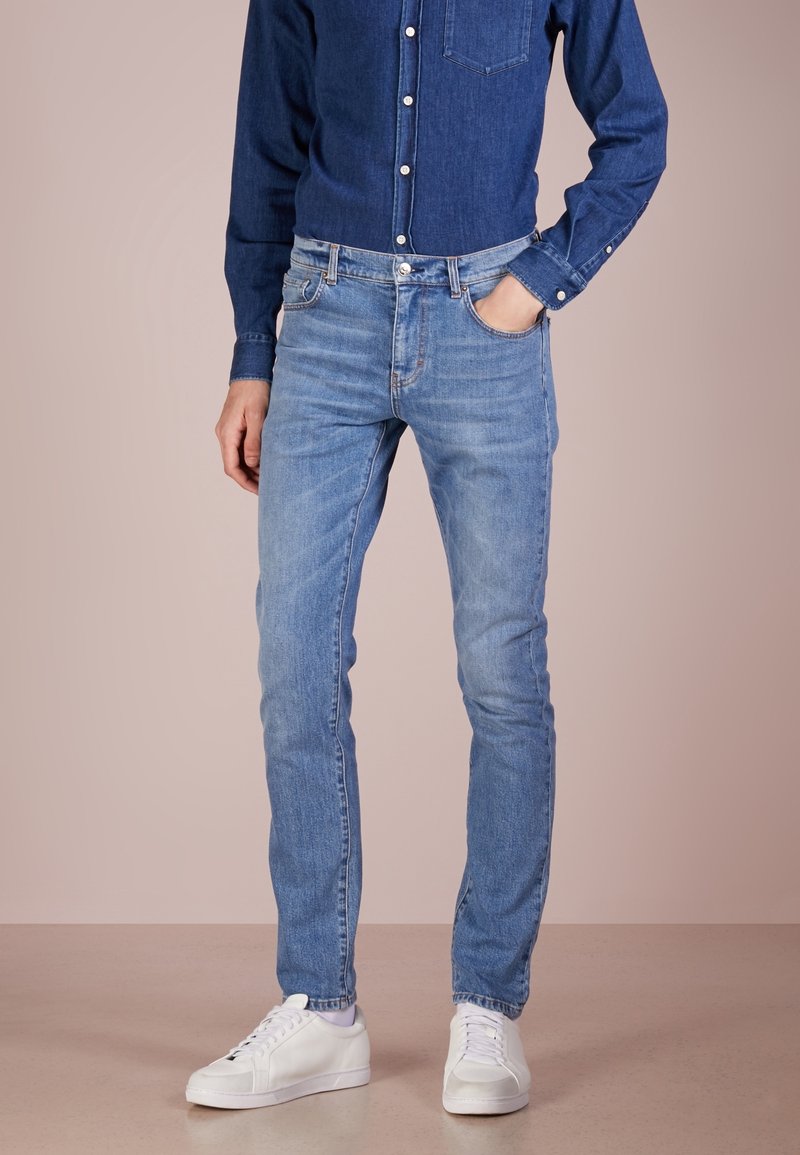 Ljusblå denimjeans med slim fit, som har fem fickor, en urtvättad textur och sydda detaljer. Matchas med vita sneakers.