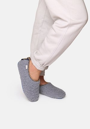 Grå, texturerade tofflor med ett mysigt, fleece-liknande material. Har en kontrasterande kedjedetalj längs den övre kanten. Platt, flexibel sula.