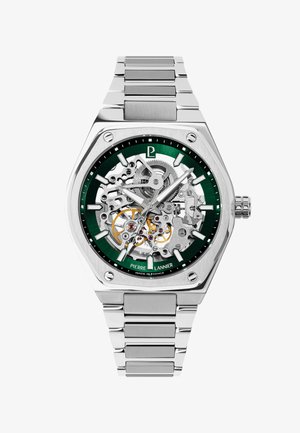 Silver metal wristwatch with skeleton dial showing internal gears, green outer ring, luminous hands, and link bracelet.