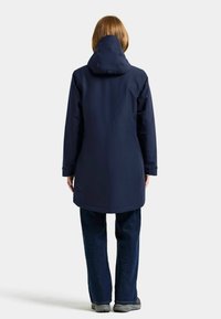 Marinblå vattentät jacka med huva, långa ärmar och rak skärning. Har en diskret logotyp på baksidan. Tillverkad av hållbart material.