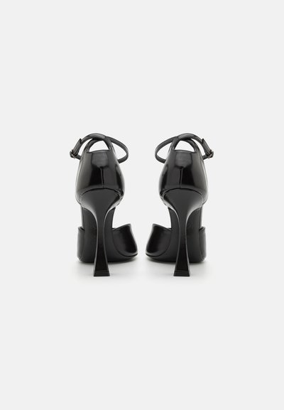 Sorte patenterede læder højhælede sko med åben ryg, tynd ankelrem og stiletto-hæl. Glat overflade, blank finish.