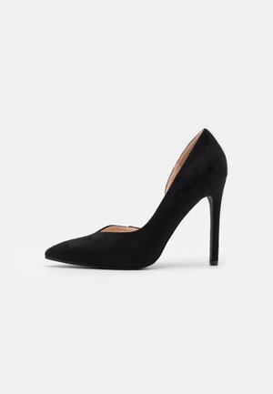 Escarpin en daim noir à talon haut avec un bout pointu et un design découpé sur le côté. Caractérisé par une texture lisse et élégante ainsi qu'un talon aiguille.