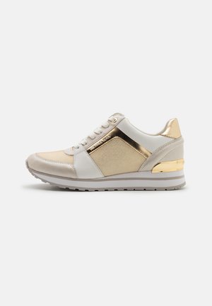 Hvid og beige sneaker med gulddetaljer, snørelukning og tekstureret sål, sidevisning på en ensartet lys baggrund.
