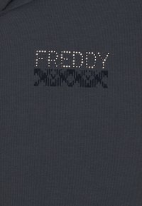 Felpa grigia scura con "FREDDY" in strass, accompagnata da un motivo grafico texturizzato sotto il testo in tonalità più scure.