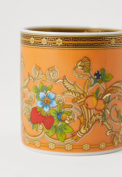 Πορτοκαλί κεραμική κούπα με περίπλοκα λουλουδένια και φρούτα μοτίβα σε μπλε, κόκκινο και πράσινο, με χρυσές λεπτομέρειες κατά μήκος της άκρης και της βάσης.