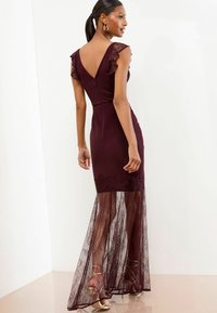 Burgunderfarbenes Abendkleid mit gerafften Spitzenärmeln, einem V-Ausschnitt im Rücken und einem durchsichtigen Spitzenrock. Es hat einen taillierten Oberkörper und filigrane Spitzenverzierungen.
