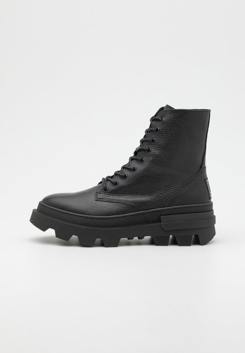 Bottes noires en cuir à lacets avec une finition texturée, bout rond et semelle en caoutchouc épaisse présentant des motifs de relief prononcés.