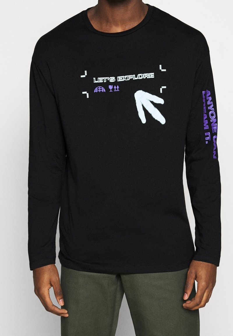 Svart långärmad tröja med grafisk text "Låt oss utforska" och symboler. Accenter i ljusblått och lila på ärmarna. Material i bomull.