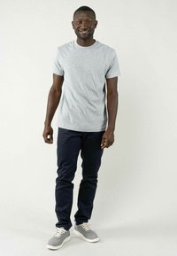Grijze katoenen t-shirt met korte mouwen, gecombineerd met marineblauwe chino's en grijze sneakers. De outfit is casual en aansluitend, geschikt voor dagelijks gebruik.
