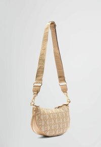 Beige shoulder bag with a rounded shape, textured fabric, and a gold-tone hardware accent. Adjustable strap features a logo pattern.