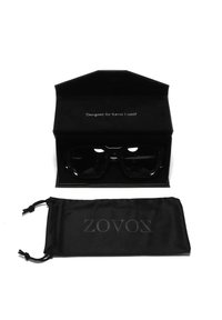 Occhiali da sole neri con una montatura spessa, forma leggermente angolare e lenti scure, presentati in una custodia di velluto nera con la scritta 'Designato per Kevin Lutolf' all'interno. Include un sacchetto nero con la dicitura 'ZOVOX' stampata.