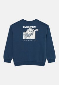 Sweatshirt azul marinho de mangas compridas, apresentando um gráfico de montanha e texto branco nas costas. Punhos e barra canelados. Textura de tecido macio.