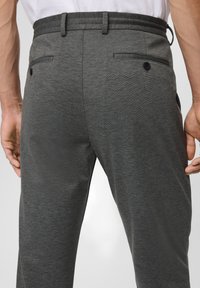 Graue, taillierte Hose aus strukturiertem Stoff, mit einem figurbetonten Bund, zwei Gesäßtaschen mit Knöpfen und dezenten Stickdetails.