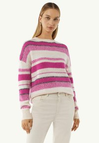 Strickpullover mit rosa, weißen und grauen Streifen. Verfügt über einen Rundhalsausschnitt und gerippte Bündchen. Kombination mit hellen Jeans.
