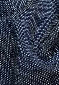 Tela tejida con una base azul marino y un patrón en forma de cuadrícula en blanco, que destaca por su superficie texturada y su caída flexible.