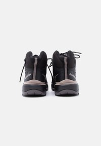 O pereche de bocanci negri de drumeție Salomon văzuți din spate, prezentând șireturile, gulerelor căptușite și tălpile exterioare texturate.