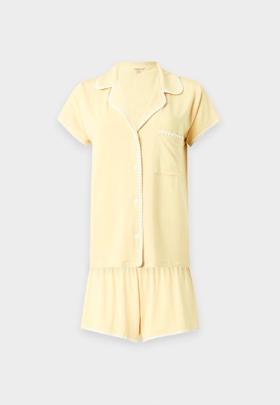Haut de pyjama jaune doux à manches courtes avec boutons, poche poitrine et short ample assorti, tous deux avec un bord blanc.