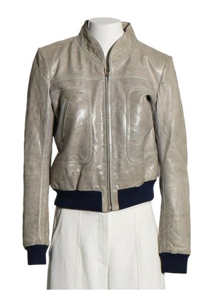 Blouson bomber en cuir gris clair avec fermeture éclair frontale, poignets et taille côtelés bleu marine, présenté sur un mannequin torse portant un pantalon blanc.