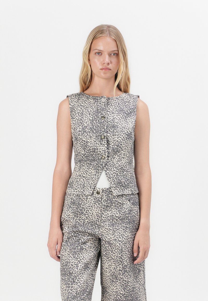 Αμάνικη, γκρι τοπ με λεοπάρ σχέδιο, στρογγυλή λαιμόκοψη, κουμπιά μπροστά και με κοψίματα στη μέση. Λείος υφασμάτινος τρόπος.