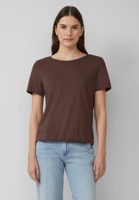 Brązowy, krótki rękaw T-shirt z okrągłym dekoltem. Wykonany z gładkiego materiału, charakteryzuje się luźnym krojem i subtelnymi detalami szycia.