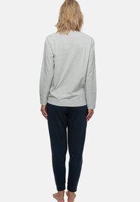 Grå långärmad t-shirt med avslappnad passform, i kombination med mörkblå sweatpants. mjukt tyg, minimalistisk design och elastiska muddar vid anklarna.