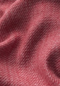 Tessuto rosso con trama a spina di pesce, caratterizzato da un aspetto morbido e tessuto, che crea pieghe e contorni delicati.