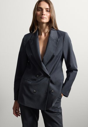 Blazer double boutonnage gris foncé en tissu tissé, avec de grands boutons, des revers en pointe et une coupe ample. Des poches sont incluses.
