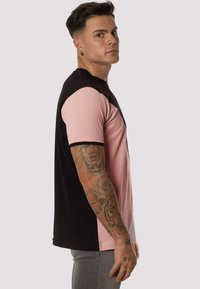 Camiseta de manga corta con bloques de color negro, rosa y blanco. Fabricada con tejido suave, cuenta con un cuello redondo y un diseño ajustado.