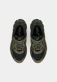 Σκοτεινά πράσινα και μαύρα αθλητικά παπούτσια με διχτυωτό ύφασμα, χοντρές σόλες και αντίθετα κορδόνια. Λογότυπο τυπωμένο στην εσωτερική σόλα.