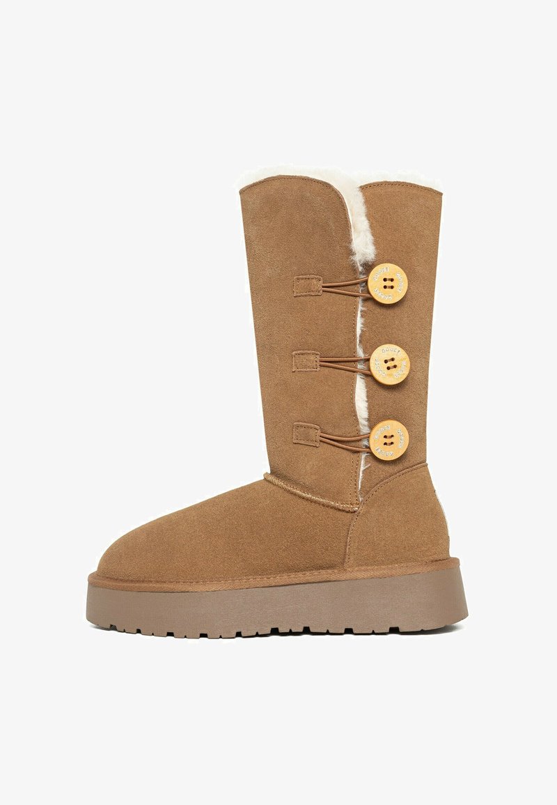 Botas de ante marrón con forro de piel sintética, tres botones decorativos de madera y suela gruesa. Presentan una puntera redonda y altura a media pantorrilla.