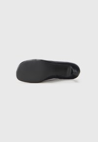 Sole di scarpa nera, materiale in gomma liscia, superficie leggermente testurizzata, forma arrotondata, con un piccolo tacco e un sottile dettaglio di branding.