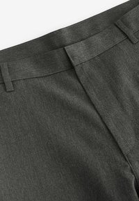Pantalon gris foncé avec une texture de tissu lisse, doté d'une taille plate et de détails de couture subtils près de l'arrière.