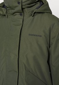 Giacca parka verde oliva con una texture liscia, chiusura con zip e dettagli in bottone. Presenta il logo ricamato "DIDRIKSONS" sul petto.